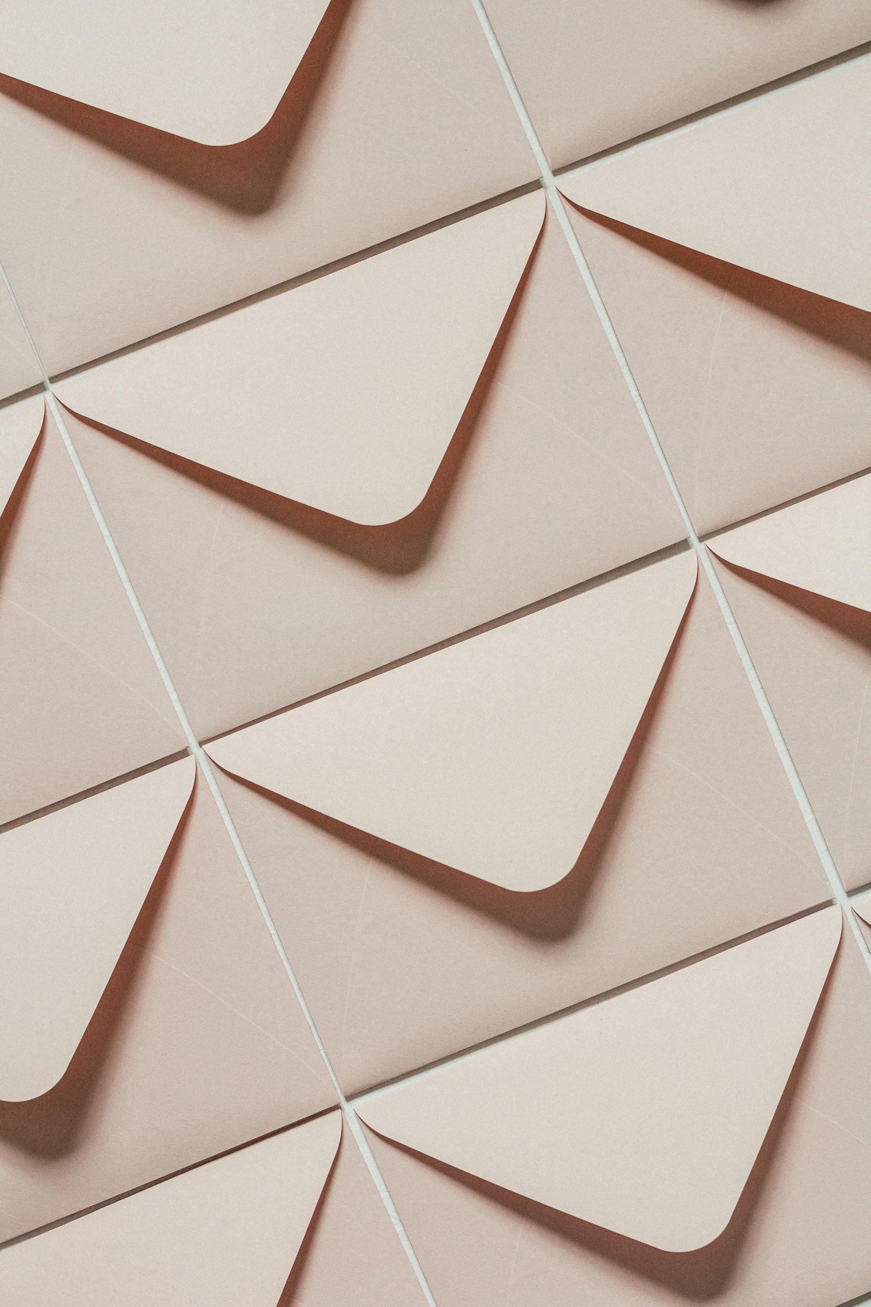 Artistic arrangement of beige envelopes creating a geometric pattern from above view.